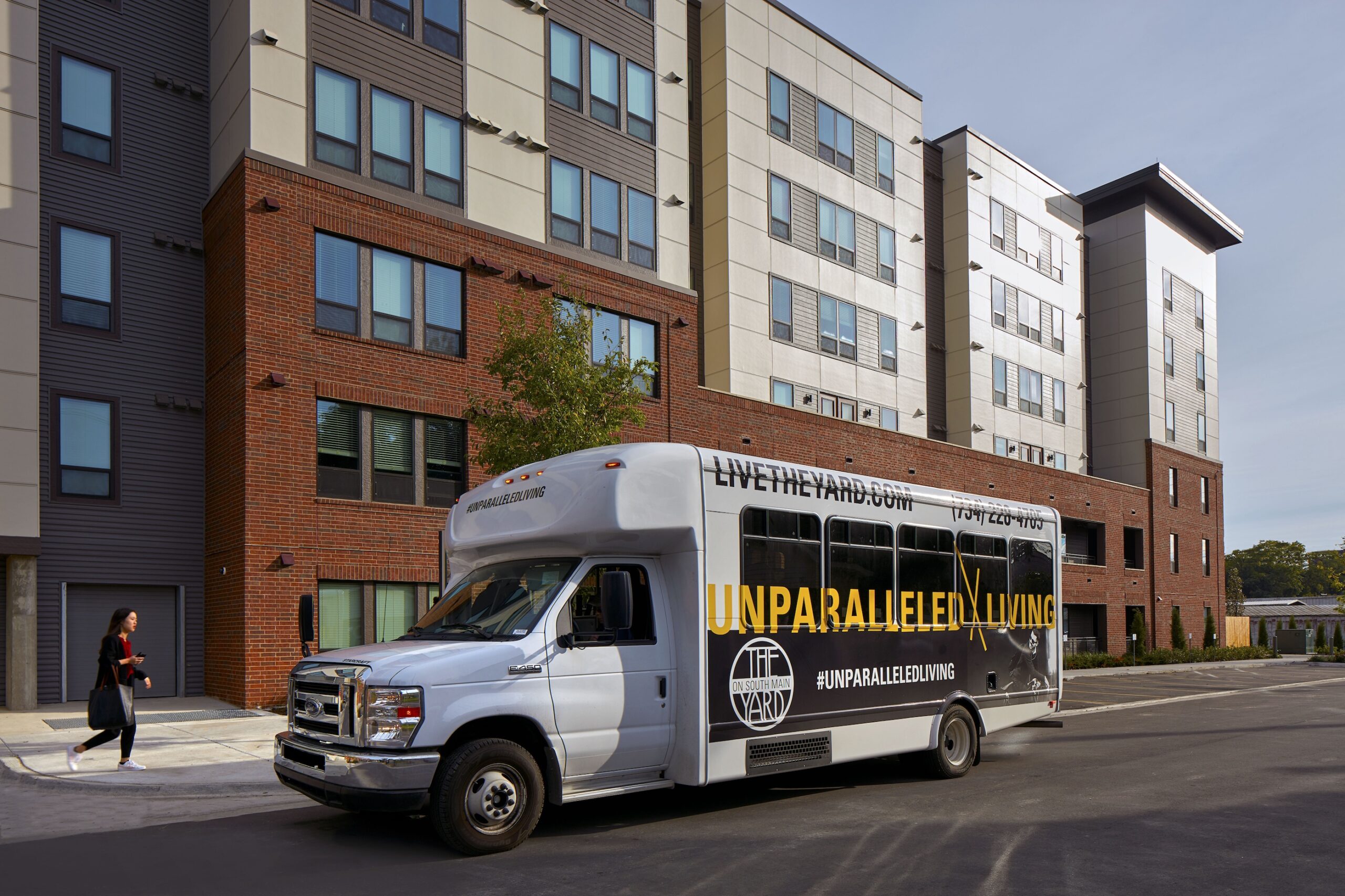 Shuttle bus with The Yard branding in front of apartment complex